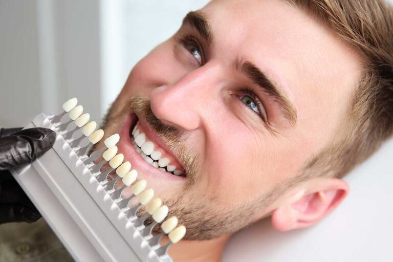 Person gently brushing their teeth in a bathroom mirror, focusing on front teeth.