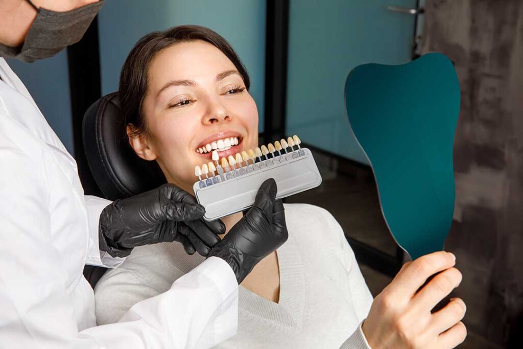 Person at home applying whitening strips to their teeth while reading instructions in a bathroom.